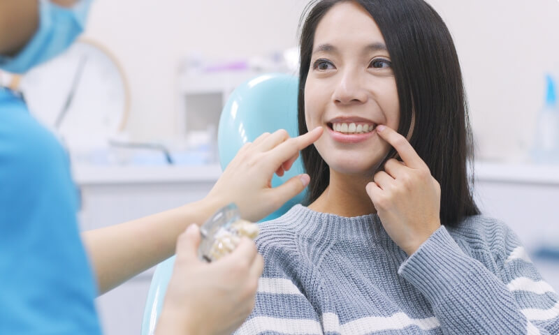 Woman pointing to smile after tooth replacement wtih full mouth dental implants